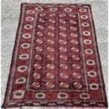 A rich red/ burgundy ground Baluchi Carpet with a Bukhara design. 290cms x 197cms.