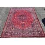 A large red ground Persian Marshad Carpet with medallion design. 380cms x 300cms.