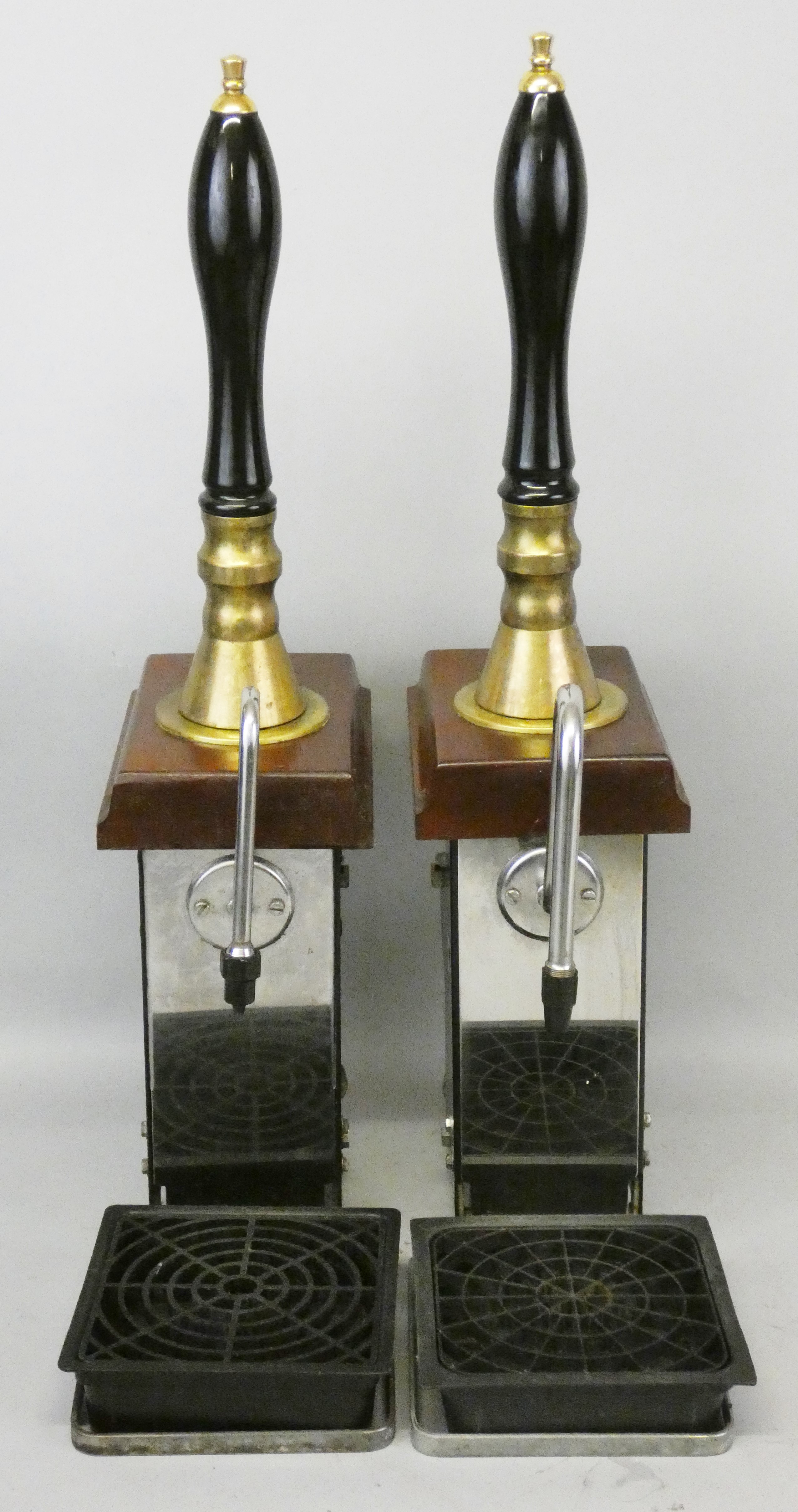 A pair of single line hand-pull beer pumps with brass mounts to porcelain handles, mounted on