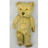 An early playworn beige teddy bear, with brown button eyes and jointed limbs, height 37cm.