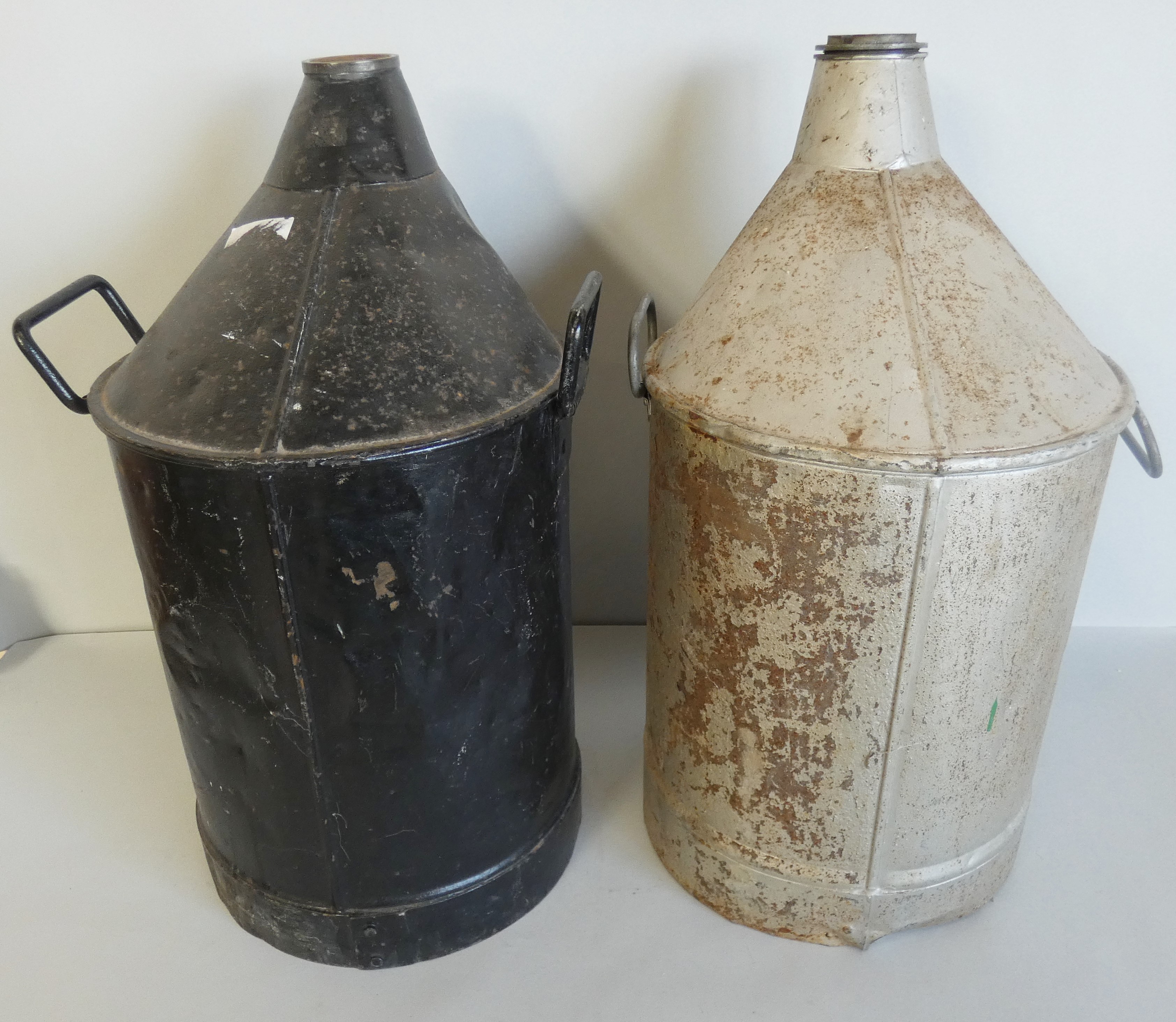 A pair of railway oil cans, one painted black and the other silver with hubcap, height 53cm (2).
