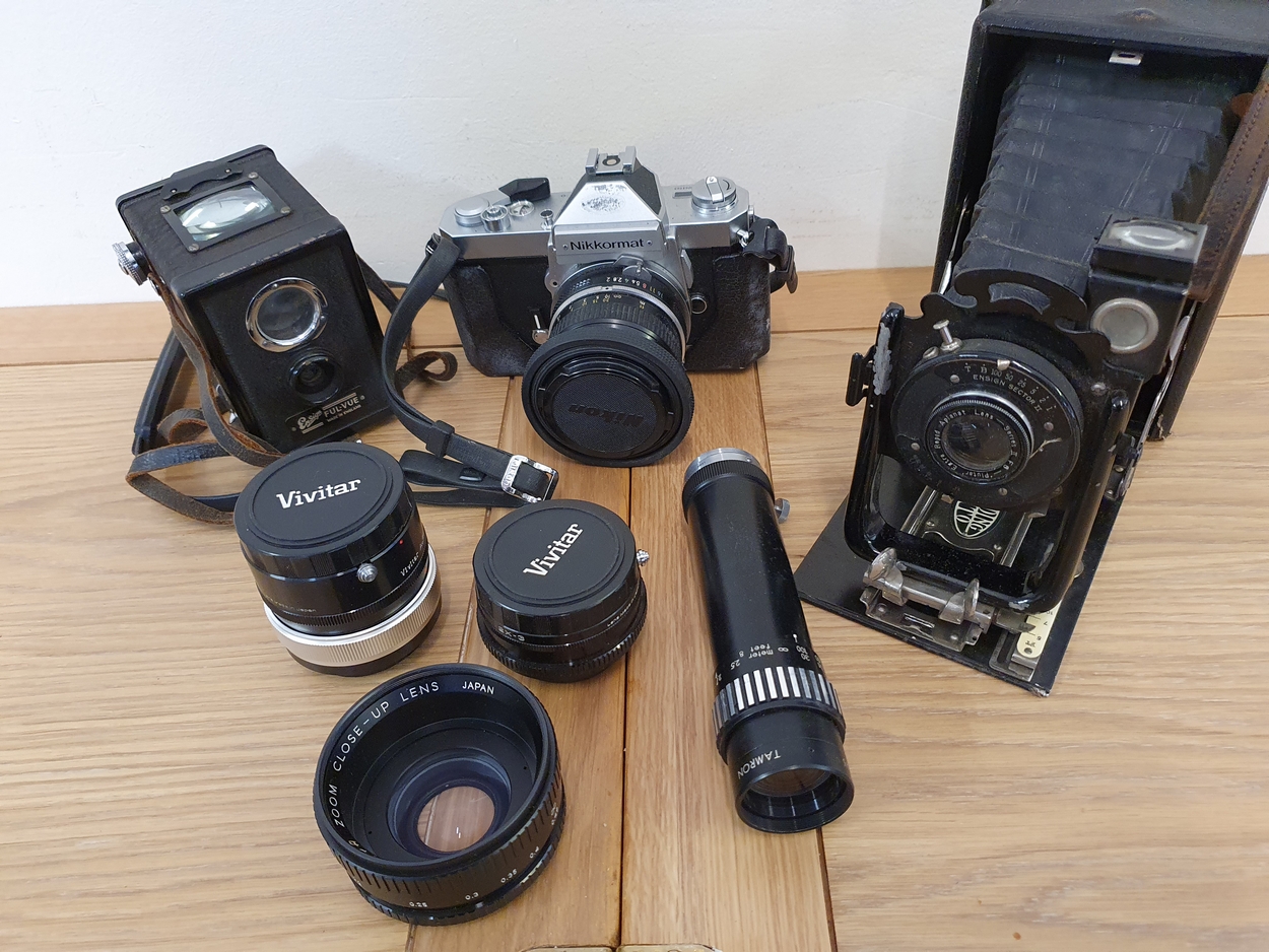 A Nikkormat FT2, 5064983 SLR camera with Nikkor 50mm lens, a Folding Klito camera, an Ensign box