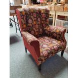 A wing back armchair with tapestry upholstery.
