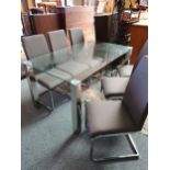 A glass and chrome dining table 150 x 90 cm together with six grey fabric and chrome chairs (7).