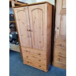 A small pine wardrobe, of two doors over three drawers, 70 x 52 x 145 cm.