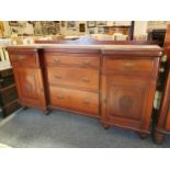 An Edwardian reverse breakfront mahogany sideboard, the central three tapering drawers flanked by