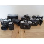 A collection of cameras, to include a Nikon F2 camera body and an Ensign Selfix 820 camera.