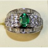 An 18ct white gold emerald and diamond dress ring, claw set with an oval mixed cut stone, weighing