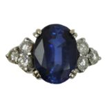 An 18ct white gold synthetic sapphire and diamond ring, claw set with an oval mixed cut stone,