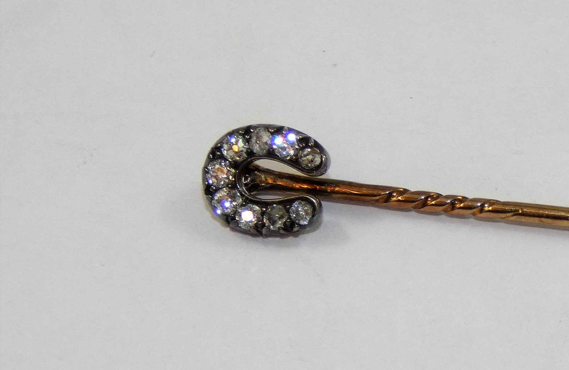 A Victorian diamond set horseshoe stickpin, silver set with nine old cut stones, total weight