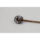 A Victorian diamond set horseshoe stickpin, silver set with nine old cut stones, total weight