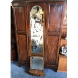 An Edwardian mahogany bow front wardrobe, with single mirror door and carved side panels, 125 x 48 x