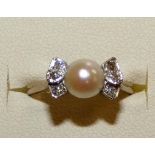 An 18ct white gold pearl and diamond ring, peg set with a cultured bead of 6mm, single cut diamond