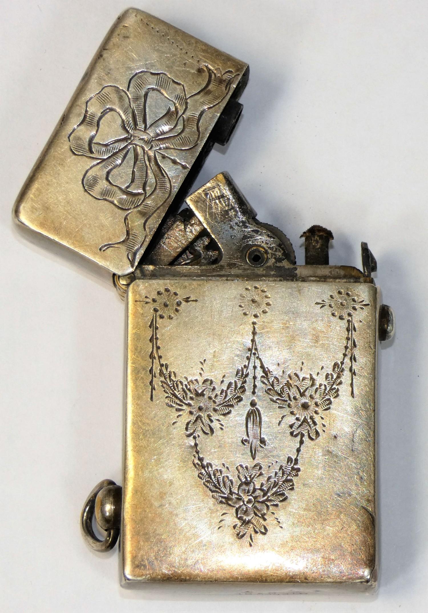 An Edwardian Sterling Silver petrol lighter, stamped sterling silver case, with ribbon and garland