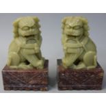 A Chinese pair of soapstone Dogs of Fo, the green dogs mounted on brown bases, height 9.5 cm.