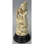 An early 20th century Indian ivory figurine, carved to depict a lady playing a flute, mounted on