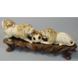 A Chinese Ivory figure group, carved to depict two lions fighting over a puzzle ball with another