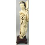 A Japanese ivory Okimono, in the form of a lady with a chrysanthemum and fan, black hair,