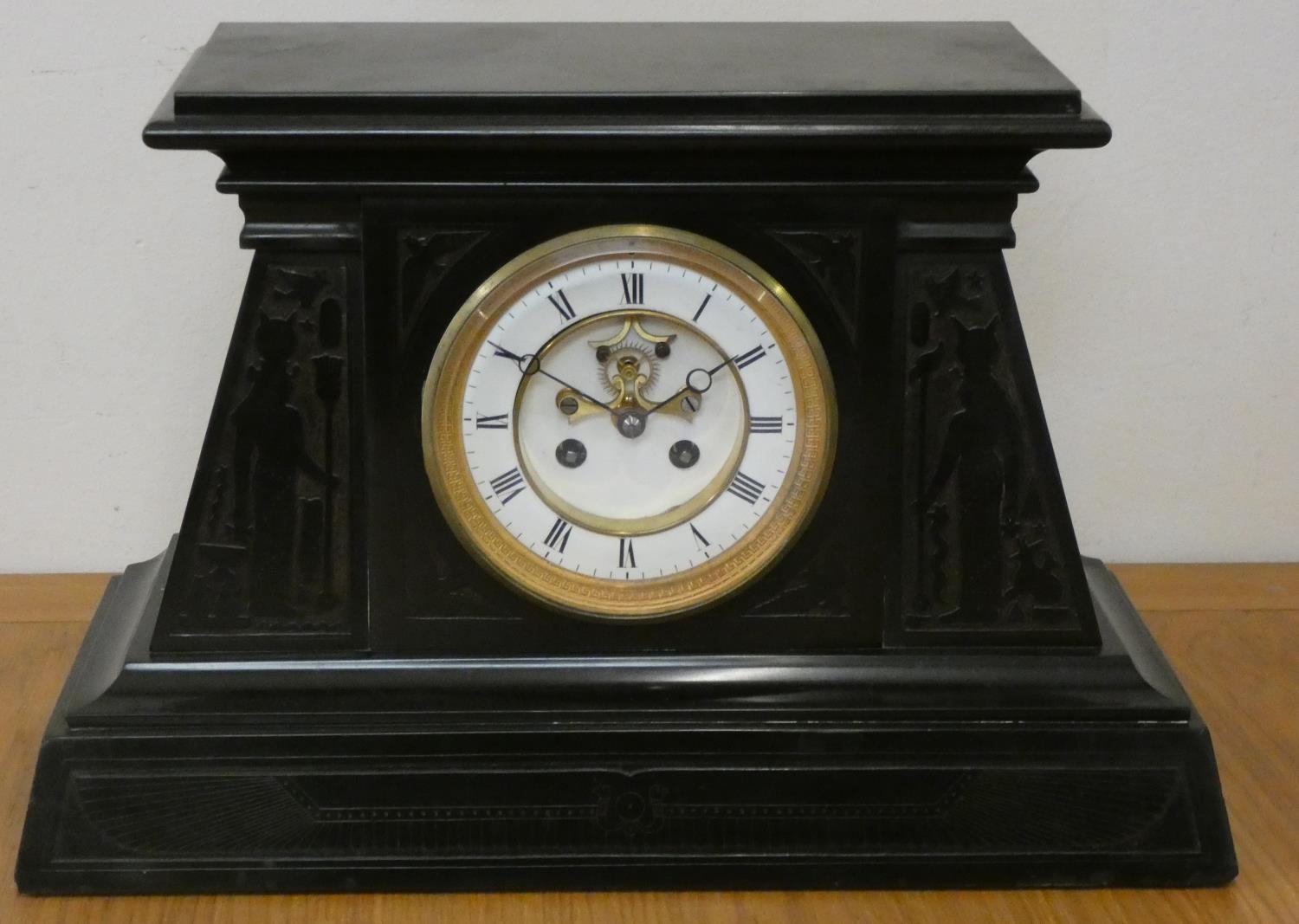 An Egyptian Revival black slate clock garniture, the white enamel two part dial with visible