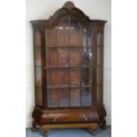 A Dutch walnut style display cabinet, with astragal glazed door and sides, raised on a bombe base