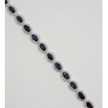 An 18ct white gold sapphire and diamond cluster bracelet, claw set with 24 oval mixed cut stones