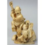 A Japanese Meiji period Ivory Okimono, carved to depict a man and boy dancing with a drummer,