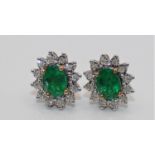 A pair of 9ct gold, emerald and diamond cluster ear studs, claw set with an oval mixed cut stone,