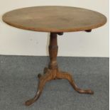 A Georgian oak circular tilt top table, raised on a turned pedestal to a trefoil legs, diameter 91