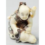 A Japanese Ivory Netsuke, carved and painted as a crouching bowman with a rabbit, height 4 cm.