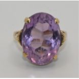 A 14 ct gold amethyst single stone ring, stamped 585, claw set with an oval mixed cut stone, 18 x 13