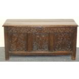 An 18th century and later oak coffer, with two plank lid, the front with three carved floral panels,