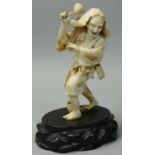 A Japanese Meiji period Ivory Okimono, carved to depict a farmer sowing seed with leaf hat,