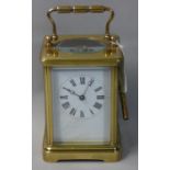 A brass cased striking carriage clock, wth white enamel dial with black Arabic numerals, the