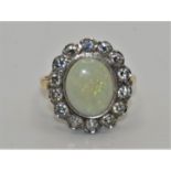 An 18ct gold opal and diamond cluster ring, collet set with an oval stone, 12 x 10 mm, bordered by