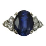 An 18ct white gold synthetic sapphire and diamond ring, claw set with an oval mixed cut stone,