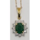 A 9ct gold emerald and diamond cluster pendant, claw set with an oval mixed cut stone, measuring 9 x