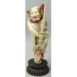 A Japanese ivory Okimono, in the form of a warrior with drawn sword and bats at his feet, painted