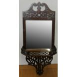 An Edwardian mahogany mirrored shelf, with fretwork surmount and support. bevelled glass, 64 cm.