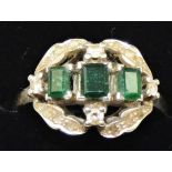 An 18ct gold emerald and diamond dress stone ring, claw set with three emerald cut stones,