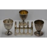 Three silver egg cups, various dates and a silver toast rack, Sheffield 1937, 4 oz (4)