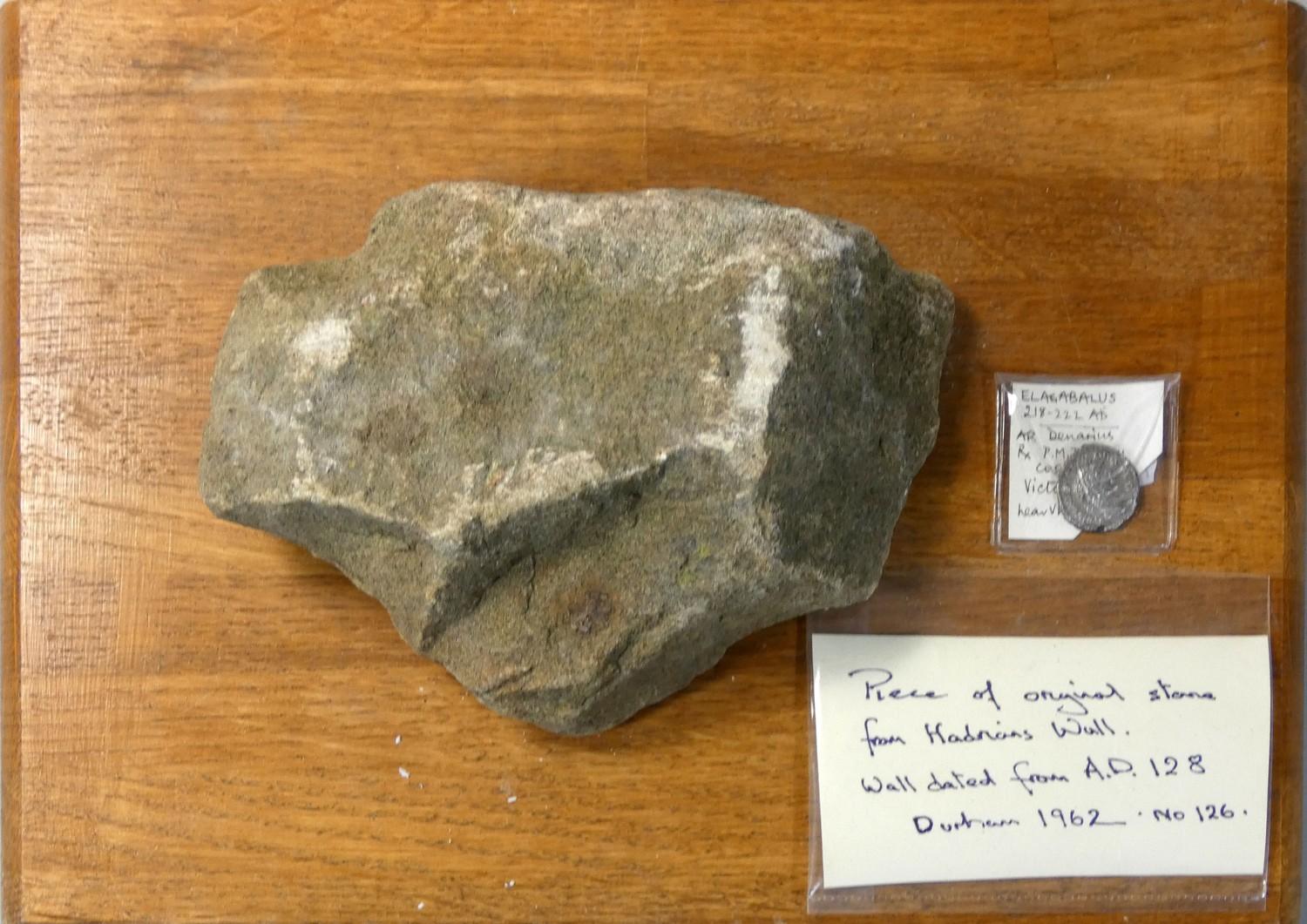 An Elagabalus (AD 218 - 222) coin and a piece of rock from Hadrians wall, mounted.