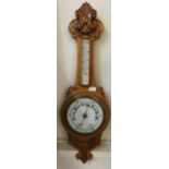 A carved oak wall hanging aneroid barometer.