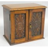 An Edwardian oak smokers cabinet, the panel doors carved with floral decoration, opening to reveal