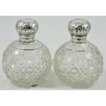 A pair of silver capped cut glass scent bottles, Birmingham 1904, the embossed hinged covers (one