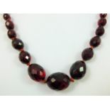 A graduated facetted cherry amber bead necklace, untested, 32 - 8 mm, length 80 cm.