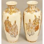 A Japanese large pair of Satsuma Meiji period vases, decorated with two dignitaries to one panel and