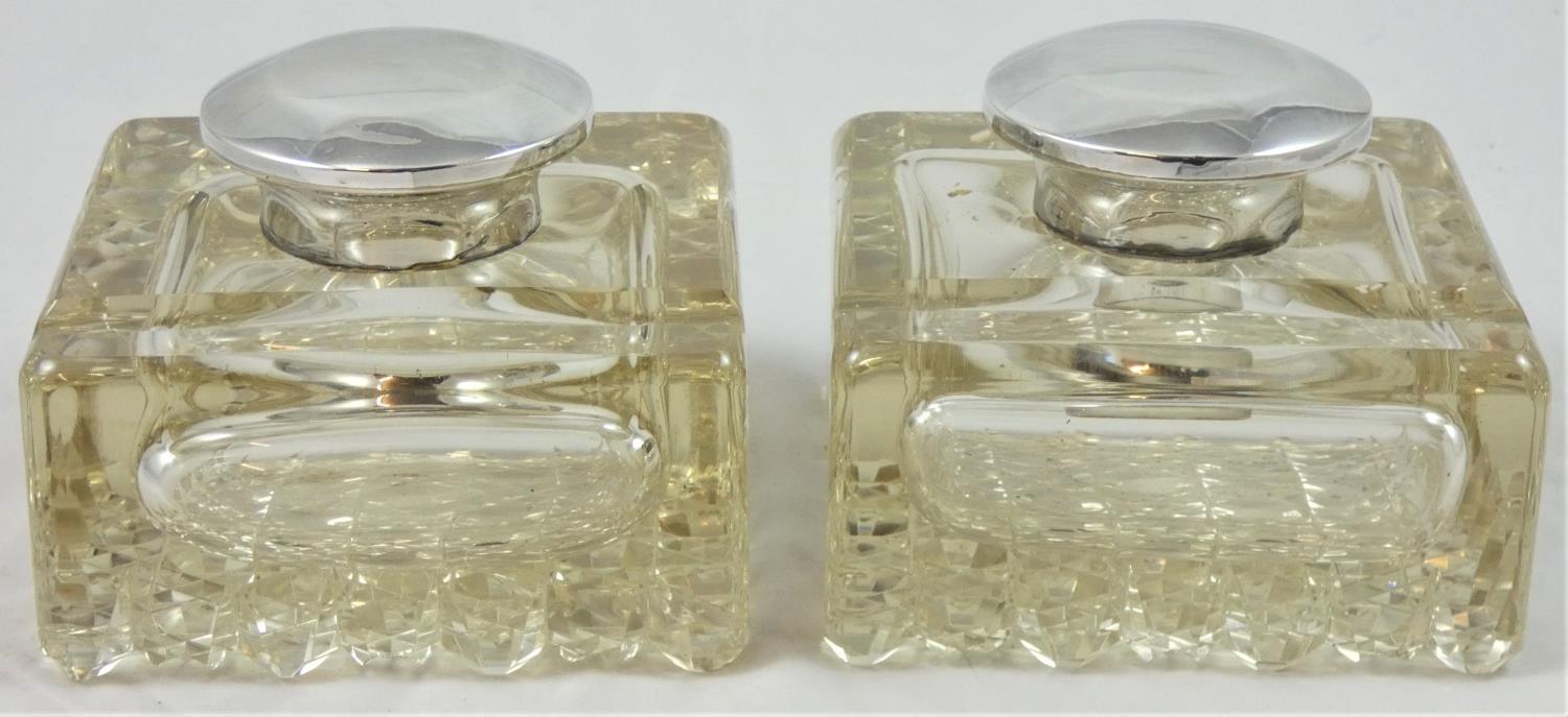 A pair of silver mounted inkwells, Birmingham 1919, the hinged cover over square bases with pen