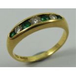 An 18ct gold emerald and diamond seven stone ring, channel set with graduated brilliant cut