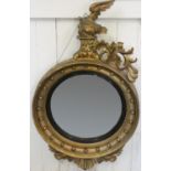 A giltwood convex circular wall mirror, with eagle and floral scroll surmount, A/F, 108 cm.