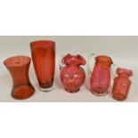 Five pieces of Victorian Cranberry glassware, to include three jugs, a trumpet vase and another vase